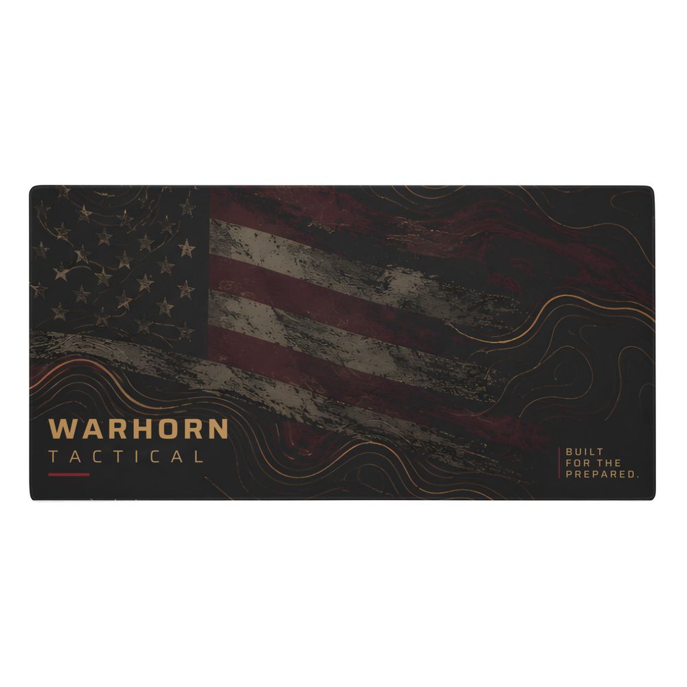 Old Glory Range Mat: weathered American flag over gold topographic lines with the WARHORN TACTICAL wordmark, angled photo of the printed mat